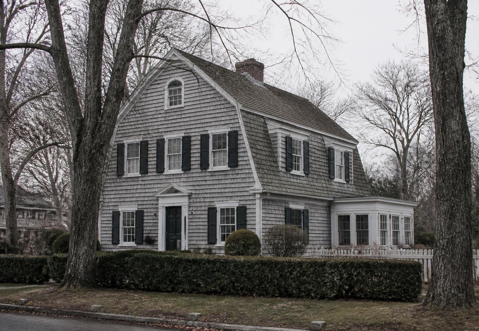 A weathered shingled colonial home on a quiet Long Island street